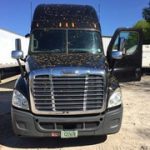 A black semi truck parked in a lot.