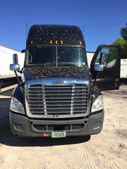 A black semi truck parked in a lot.
