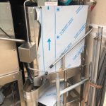 A large stainless steel washing machine is sitting in a garage.